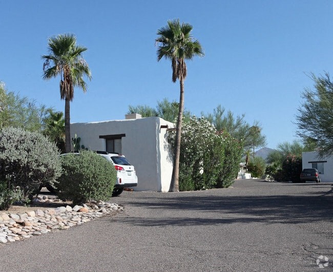 a car parked in front of a white house with palm trees