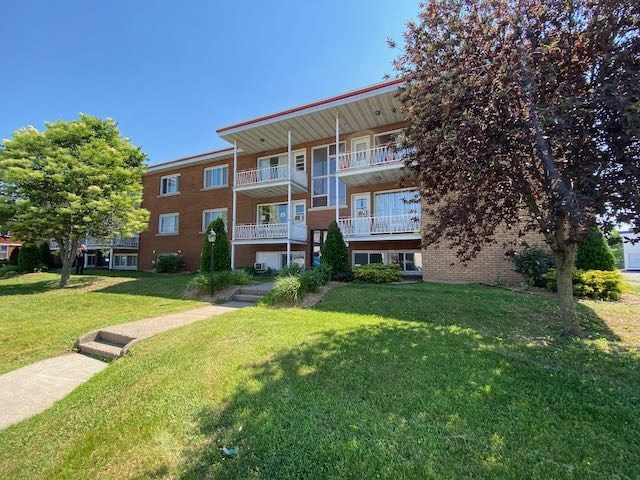 an apartment building with a green lawn and trees