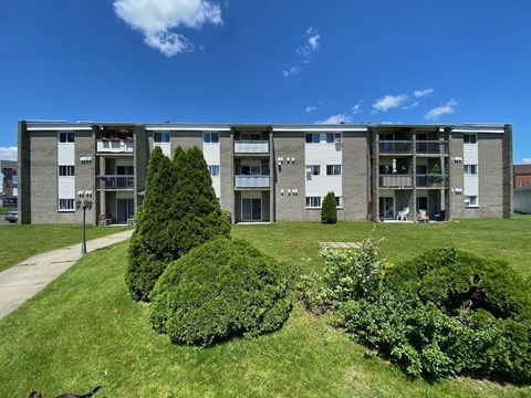 an apartment building with green grass and trees in front of it