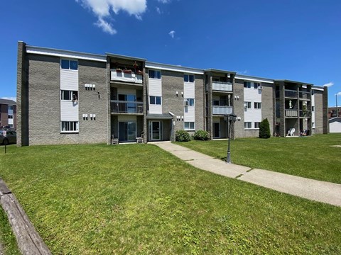 an apartment building with green grass and a sidewalk