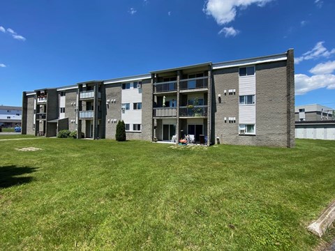 an apartment building with a green lawn in front of it