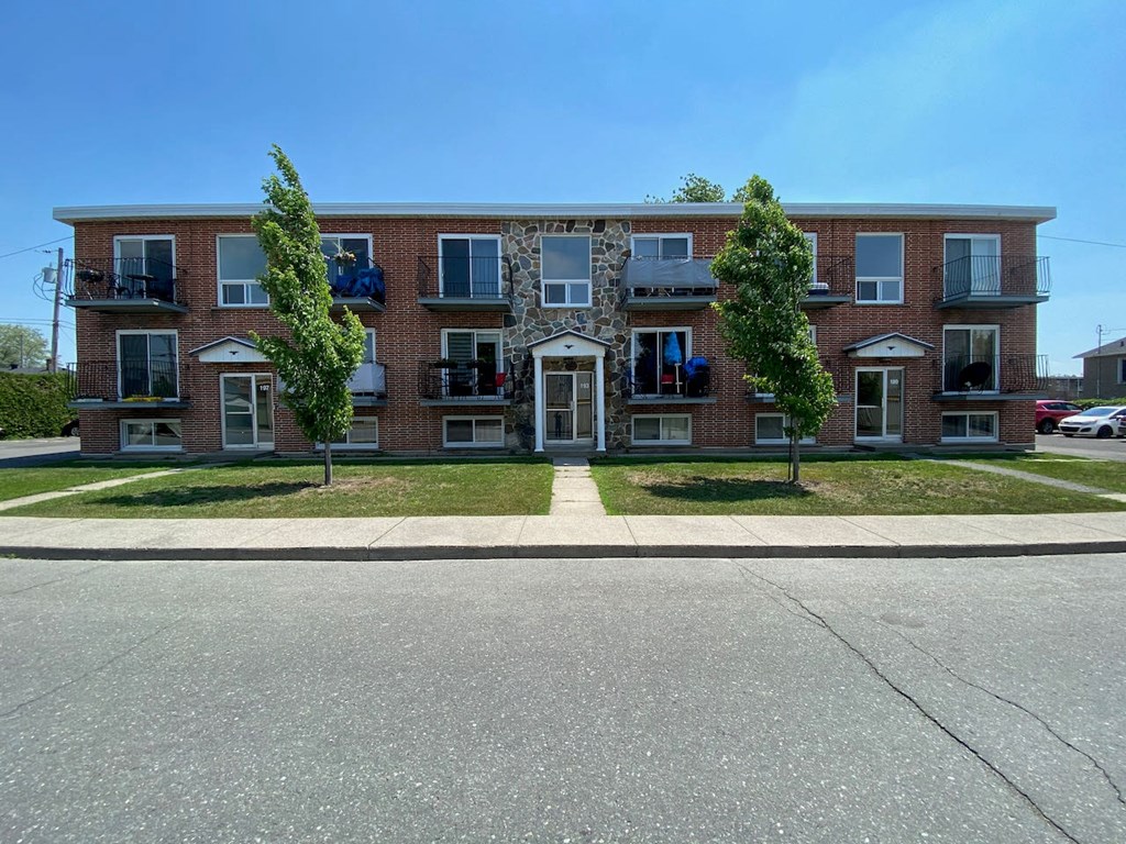 a red brick apartment building with trees in front