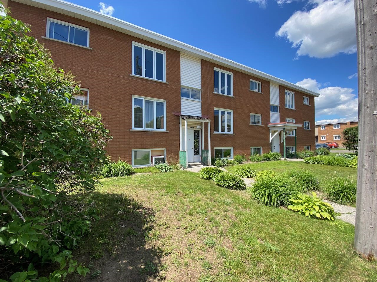 the front of a brick apartment building with a green yard
