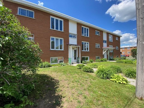 the front of a brick apartment building with a green yard
