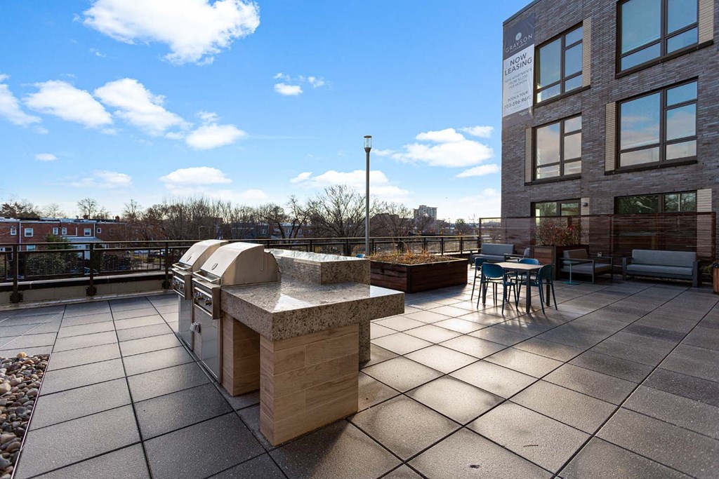 a patio with a grill and a table and chairs