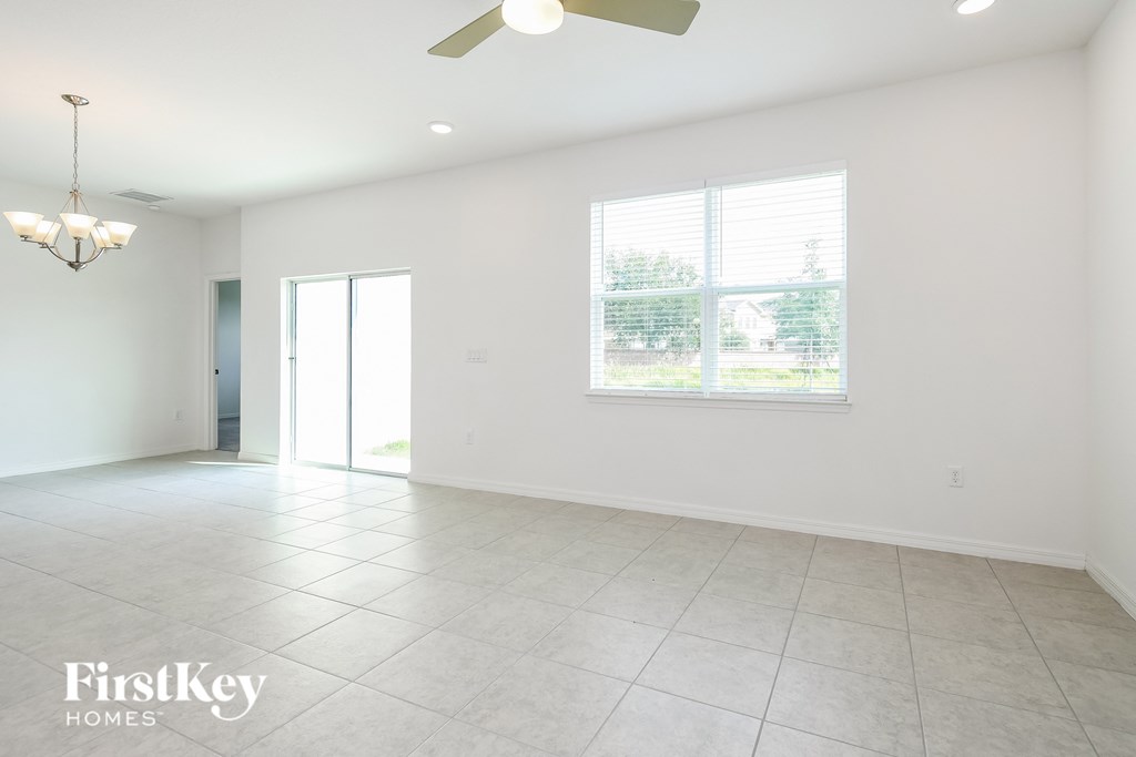 an empty living room with a window and a ceiling fan