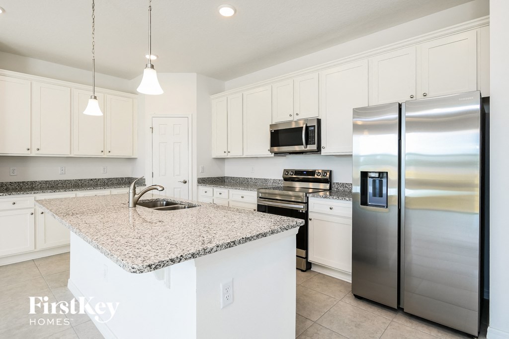 a white kitchen with stainless steel appliances and granite counter tops