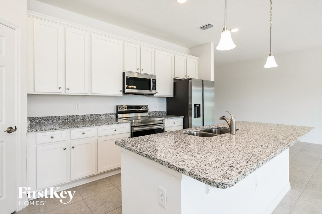 a white kitchen with granite counter tops and white cabinets