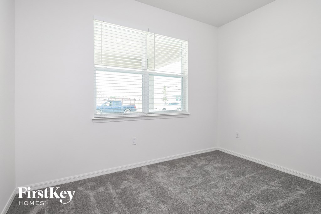 a bedroom with a large window and a carpeted floor