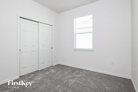 a bedroom with white walls and carpet and a window and white doors