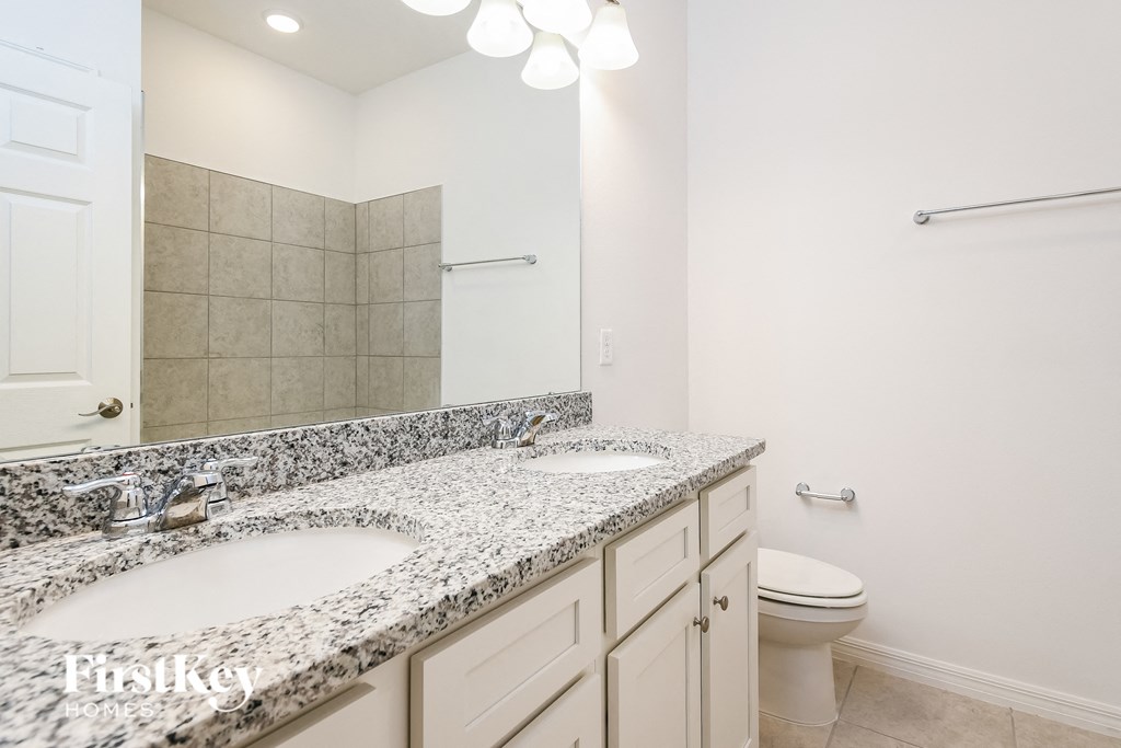 a bathroom with two sinks and a toilet and a mirror