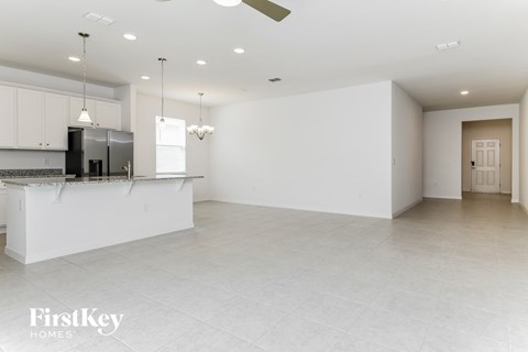 A spacious kitchen with white cabinets and a black refrigerator.