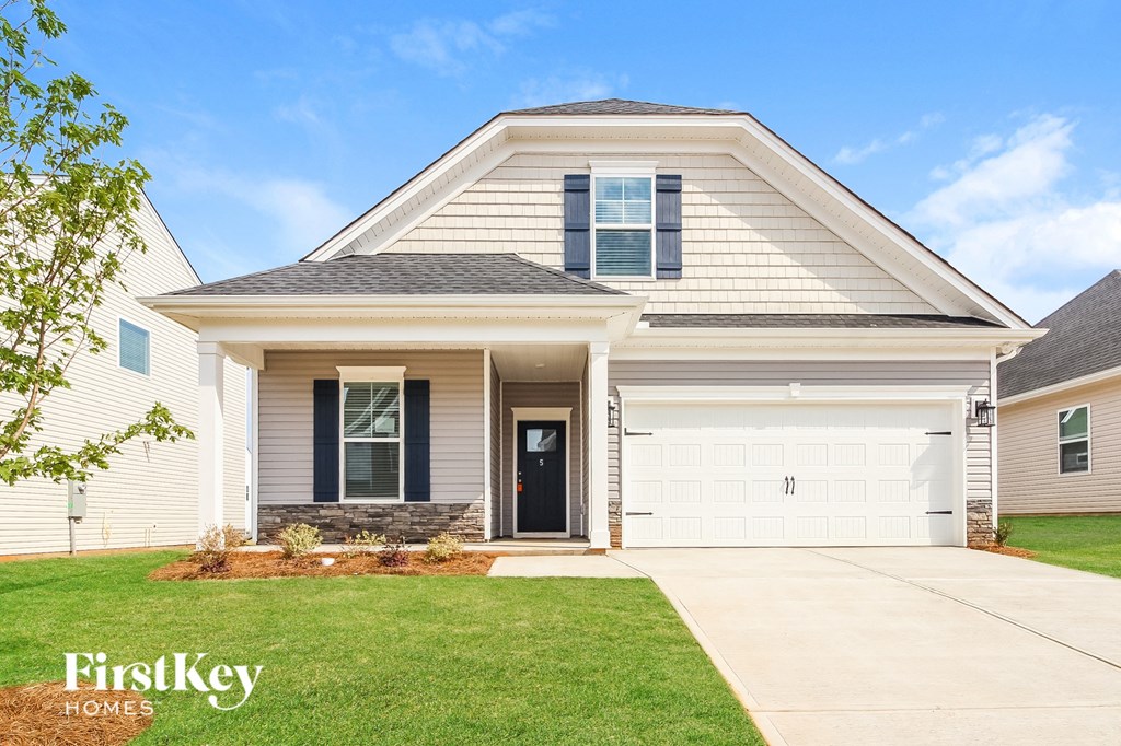 a white house with a garage door and a lawn