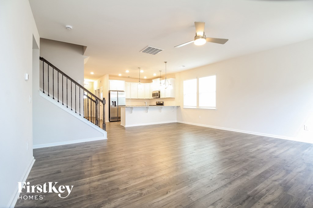 an empty living room and kitchen with wood floors and white walls