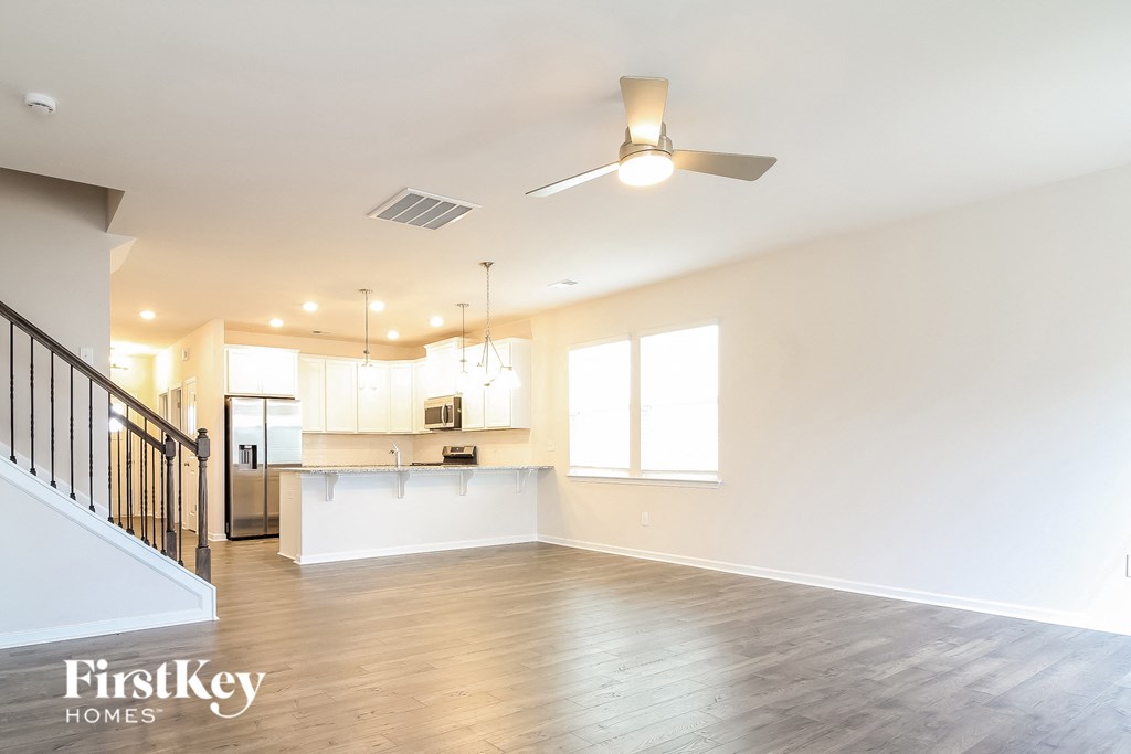 an empty living room and kitchen with a ceiling fan