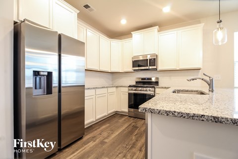 a kitchen with white cabinets and stainless steel refrigerator
