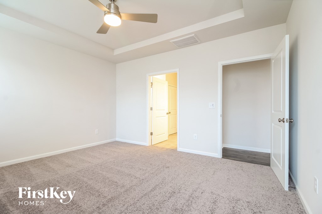 a bedroom with white walls and carpet and a door to a closet