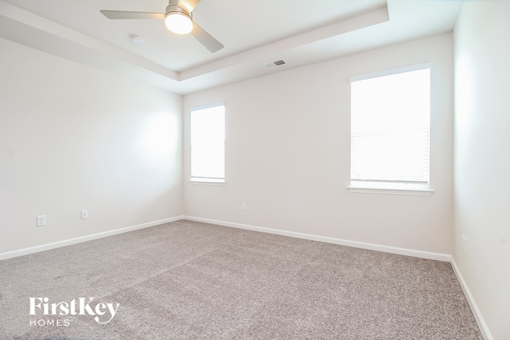 a empty room with a ceiling fan and two windows