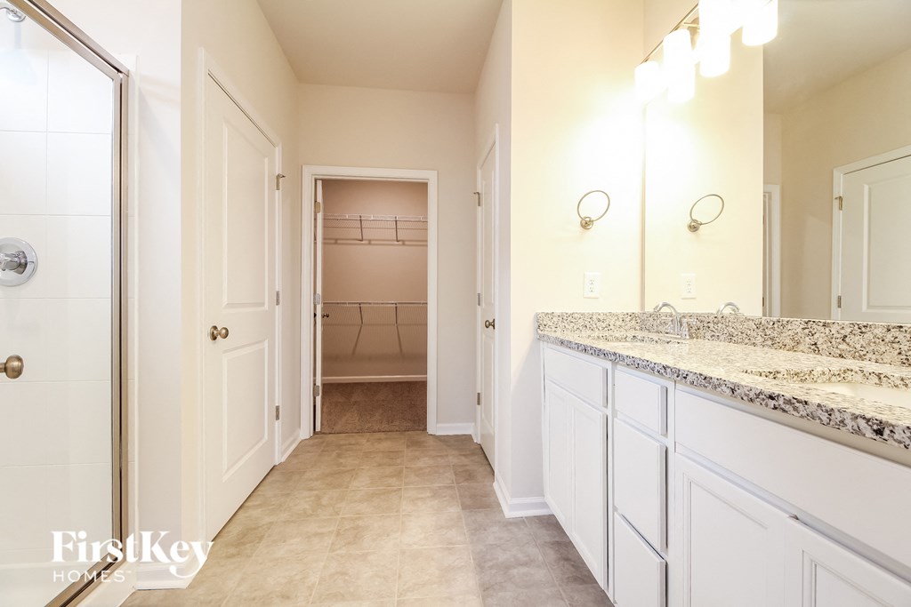 a bathroom with white cabinets and a sink and a closet