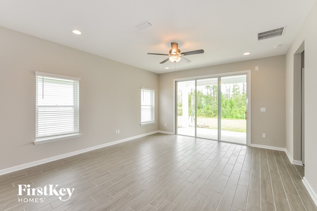 an empty living room with a ceiling fan and sliding glass doors