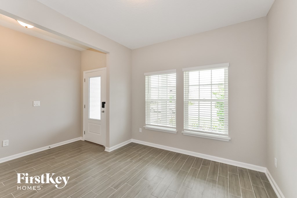 the living room of an empty house with a door and three windows
