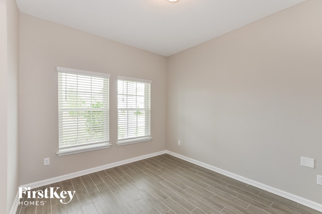 the spacious living room with hardwood floors and two windows