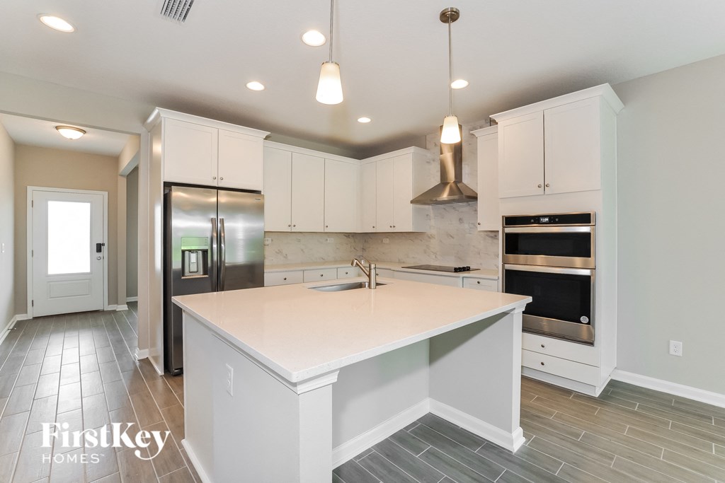 a white kitchen with a large island and stainless steel appliances