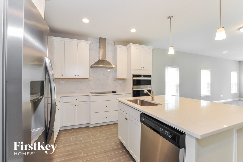 a white kitchen with stainless steel appliances and white counter tops