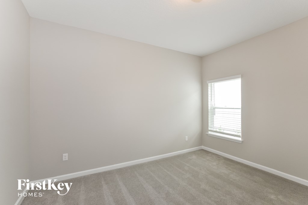 a bedroom with white walls and a window