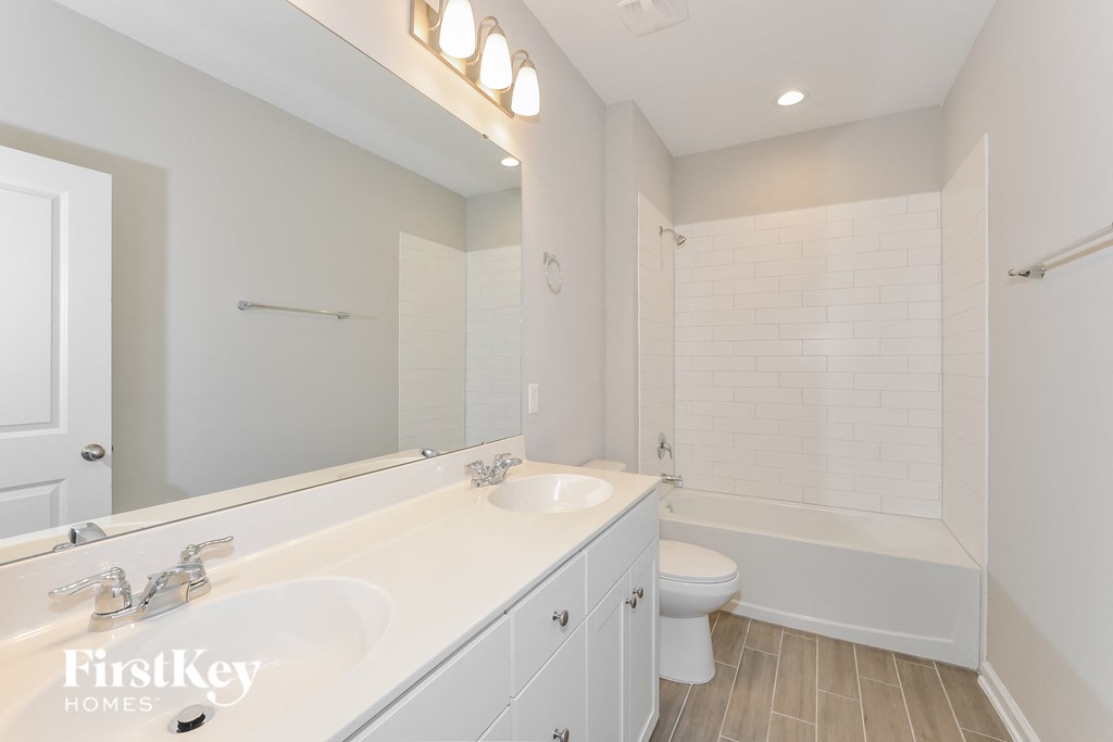 a white bathroom with two sinks and a toilet and a shower