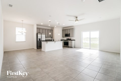 A spacious kitchen and living room with a ceiling fan and a chandelier.