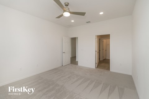a spacious living room with white walls and a ceiling fan
