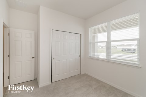 a bedroom with two doors and a window and a door to a closet