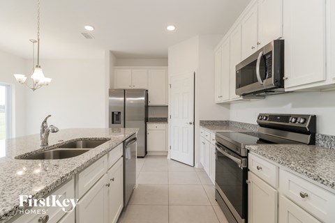 a white kitchen with granite counter tops and stainless steel appliances