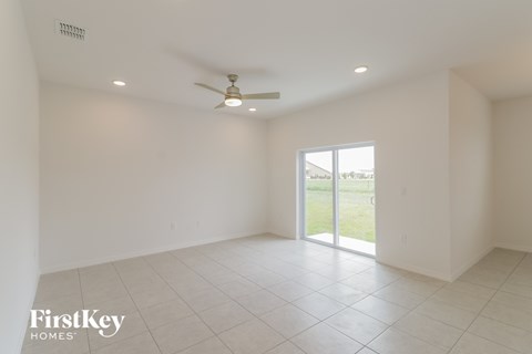 A spacious empty room with a ceiling fan and sliding glass doors.