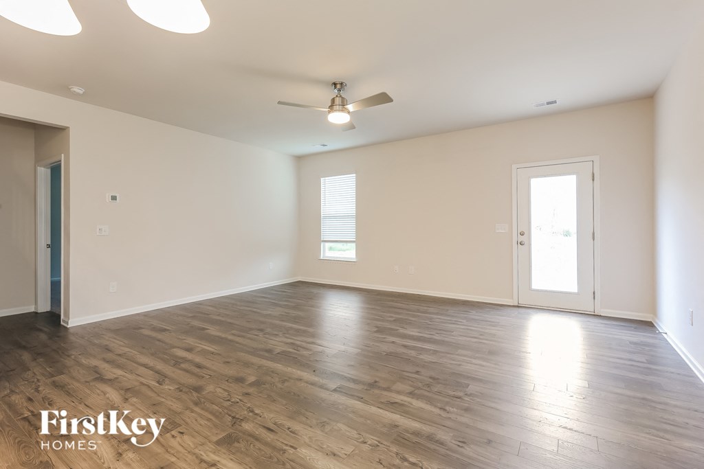 the living room of an empty house with wood flooring and a ceiling fan