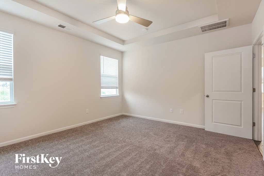 a spacious living room with white walls and a ceiling fan