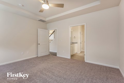 a spacious living room with carpet and a ceiling fan