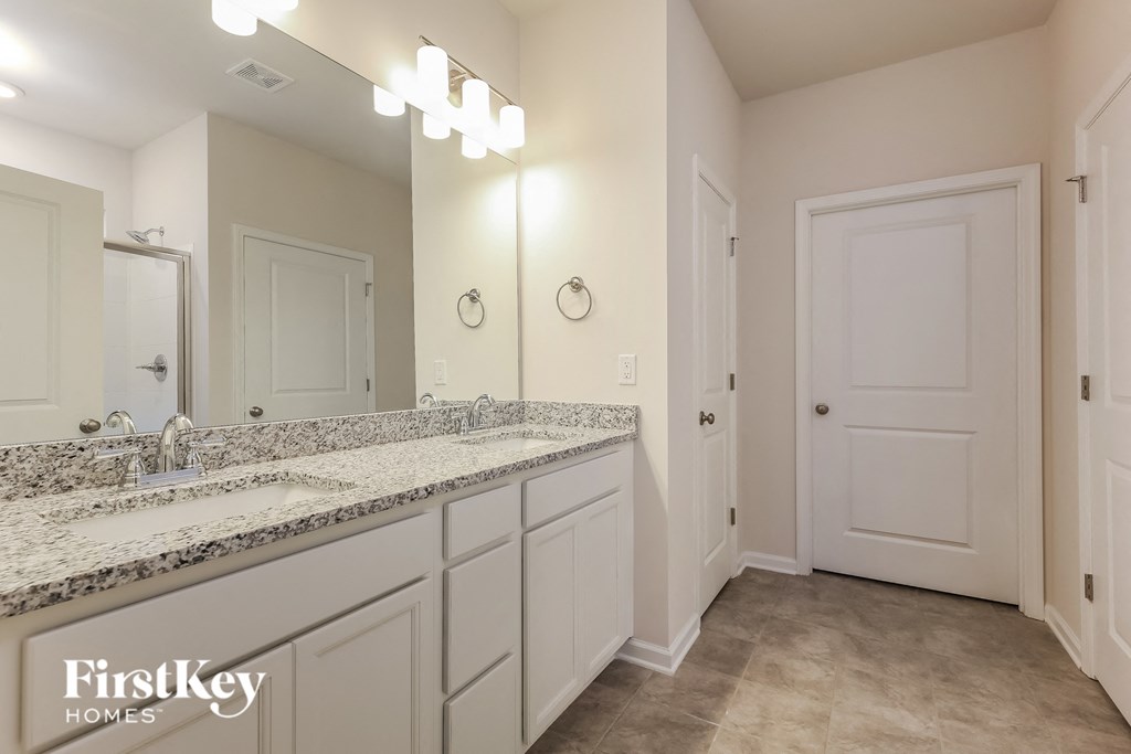 the master bathroom has dual sinks and a large mirror