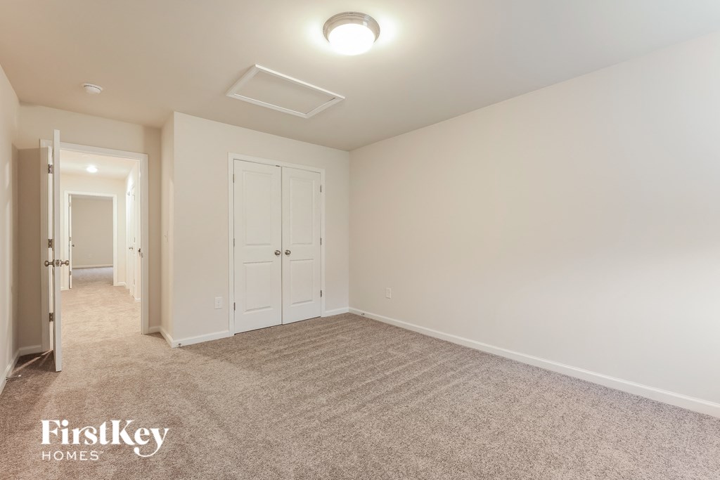 a bedroom with white walls and carpet and a door to a hallway