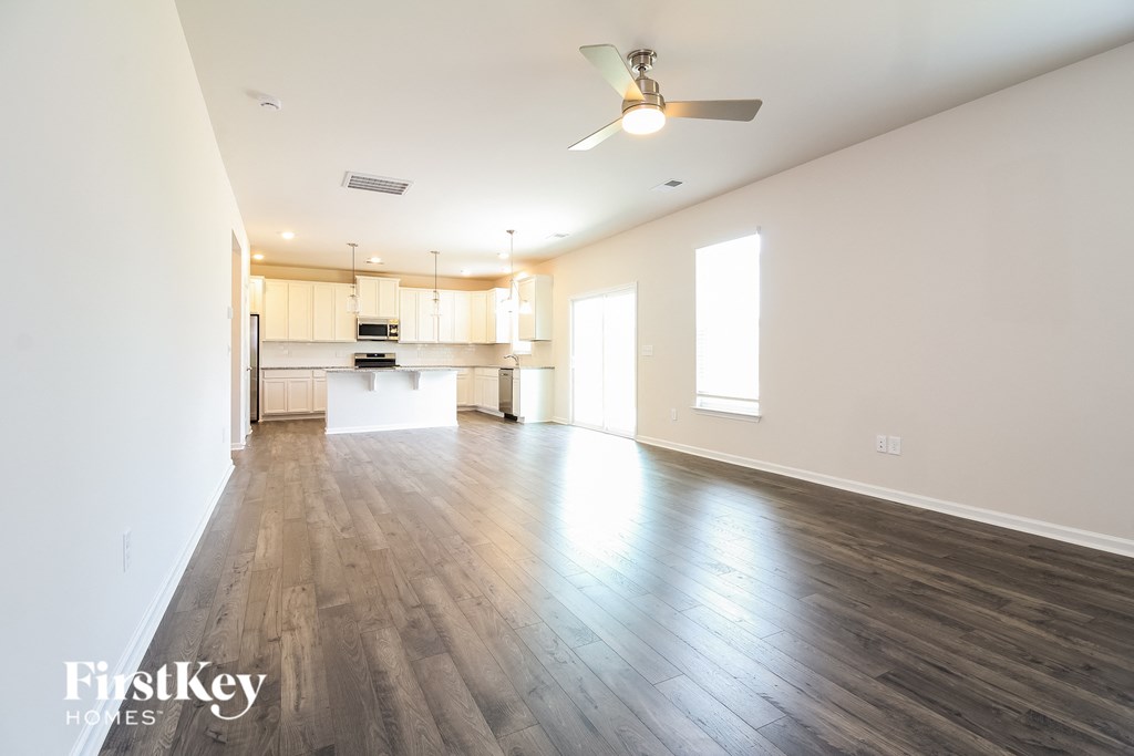 A spacious room with wooden floors and a ceiling fan.