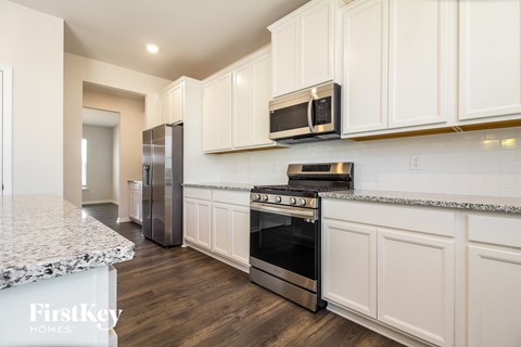 A kitchen with white cabinets and a granite countertop.