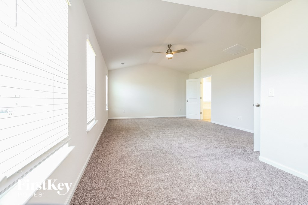 A spacious room with a carpeted floor and a ceiling fan.