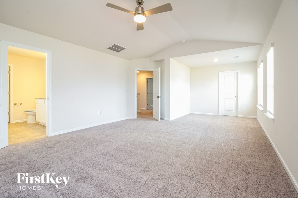 A spacious room with a carpeted floor and a ceiling fan.
