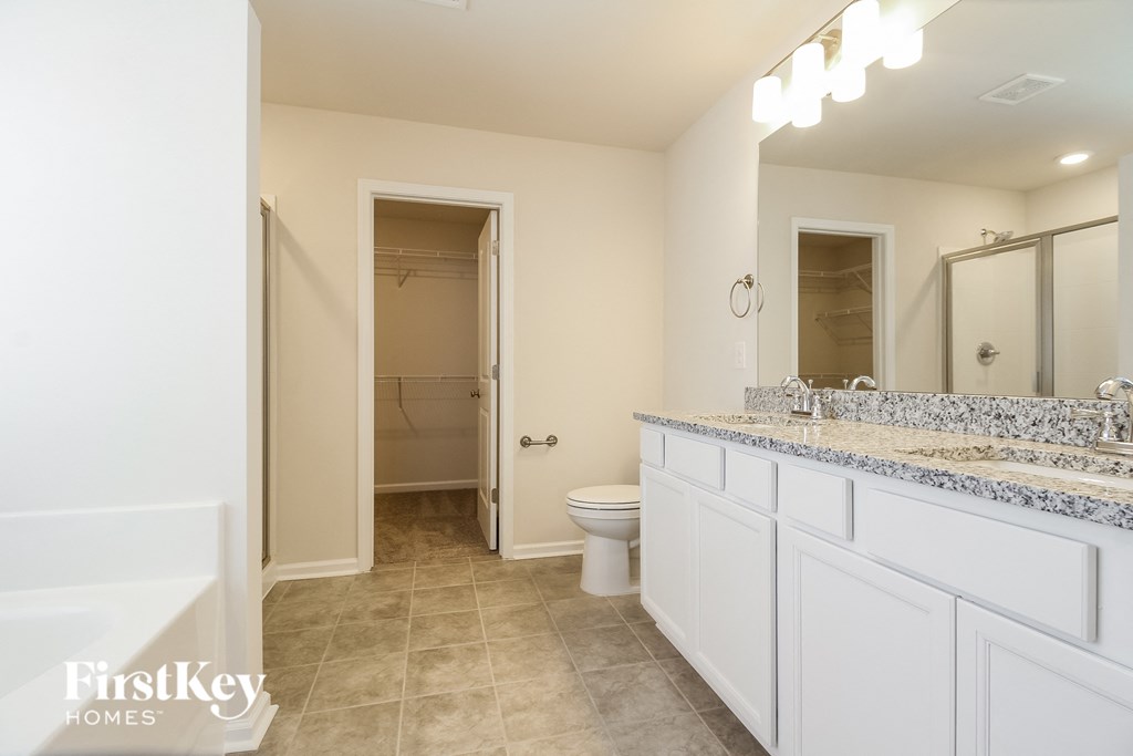 A bathroom with a toilet, sink, and mirror.