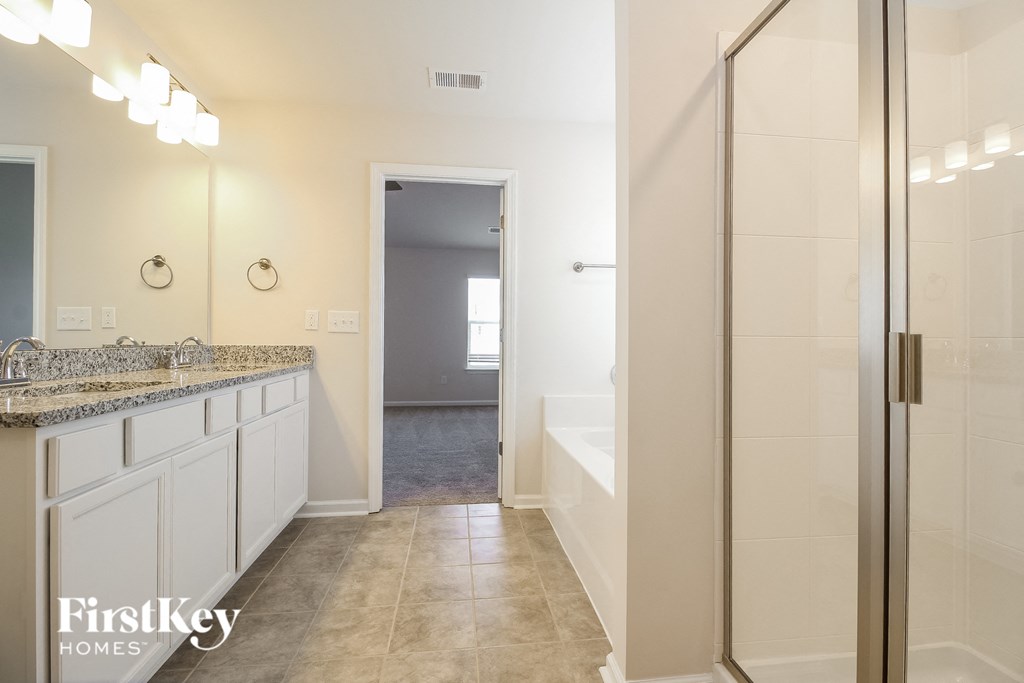 A bathroom with a sink, mirror, and shower.
