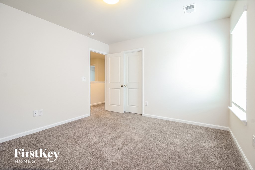 A carpeted room with a white door and a window.