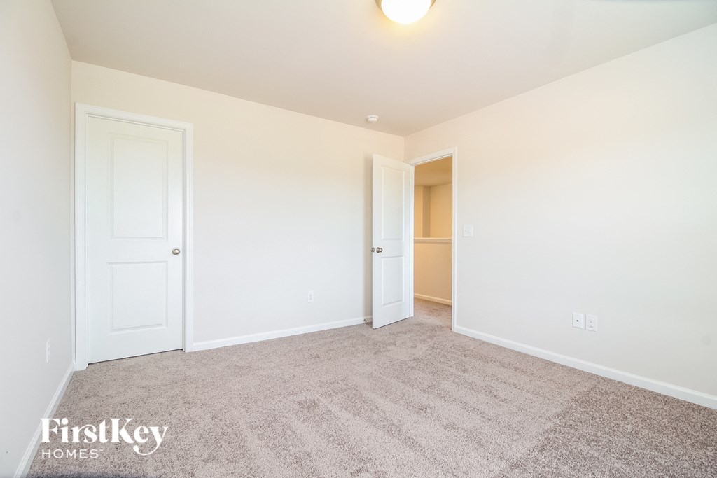 A carpeted room with a door and a window.