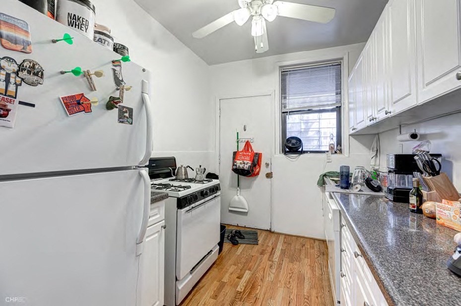 A kitchen with white appliances and wooden floors.