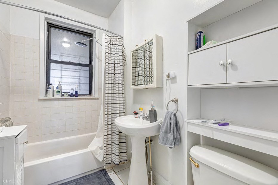 A white bathroom with a tub, sink, and toilet.